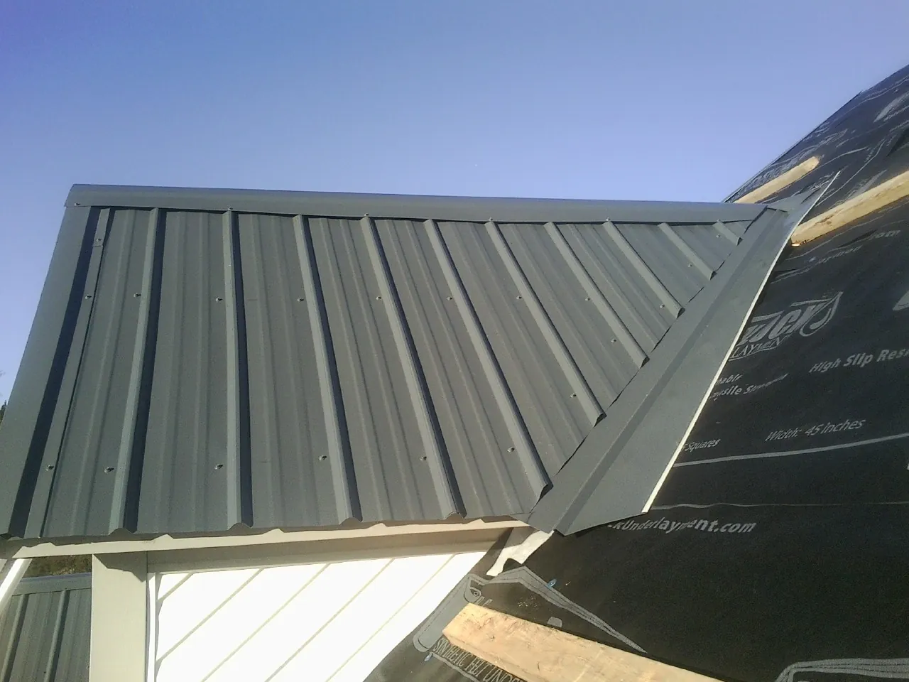 Gray metal roof panels going on over a garage gable in Henderson